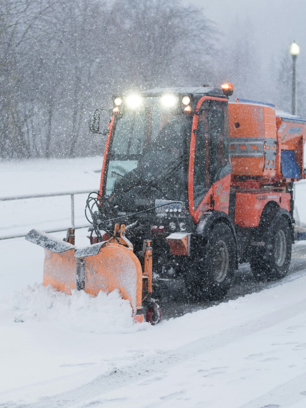Snow plow truck clearing snow during heavy snowfall